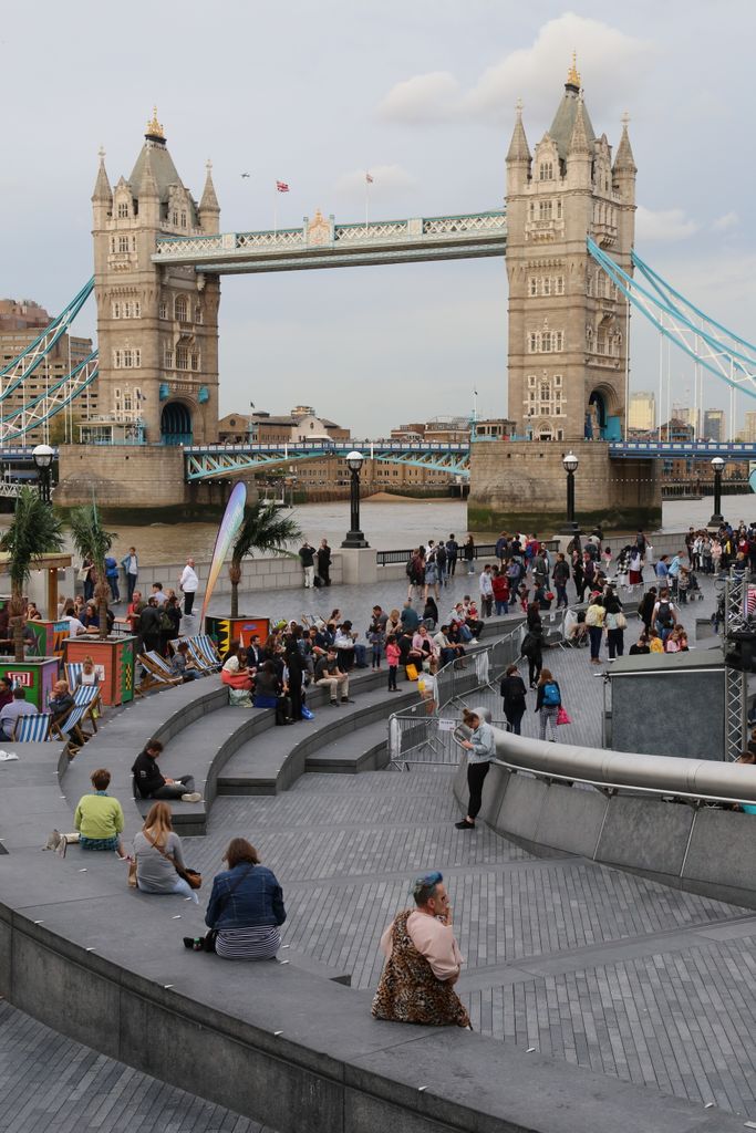 People relaxing by the Tower Bridge in London on a pleasant day.